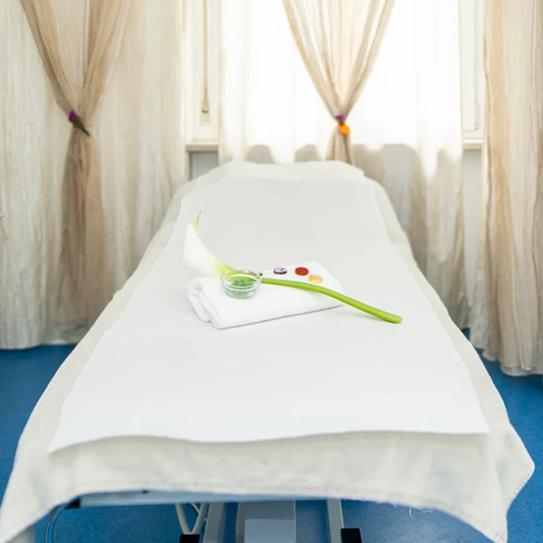 Si vede una stanza in cui vengono svolti i trattamenti estetici. Sul lettino &egrave; stato posto un asciugamano, un fiore bianco e dei sali che verranno utilizzati per i massaggi.